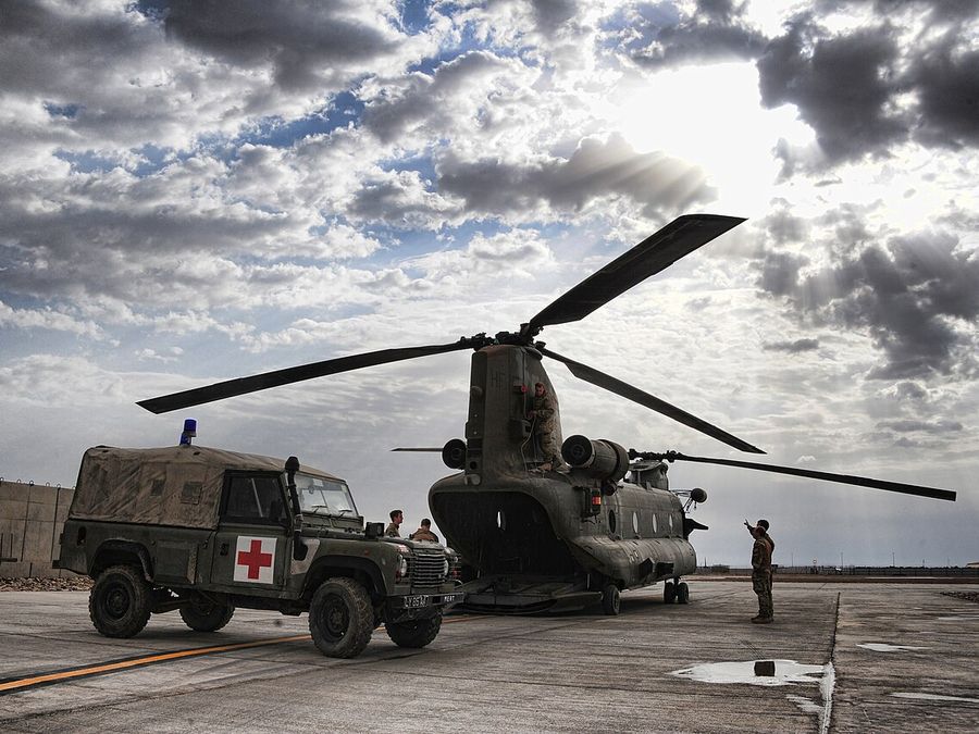 A British Army field ambulance waits beside an RAF Chinook at Camp Bastion
